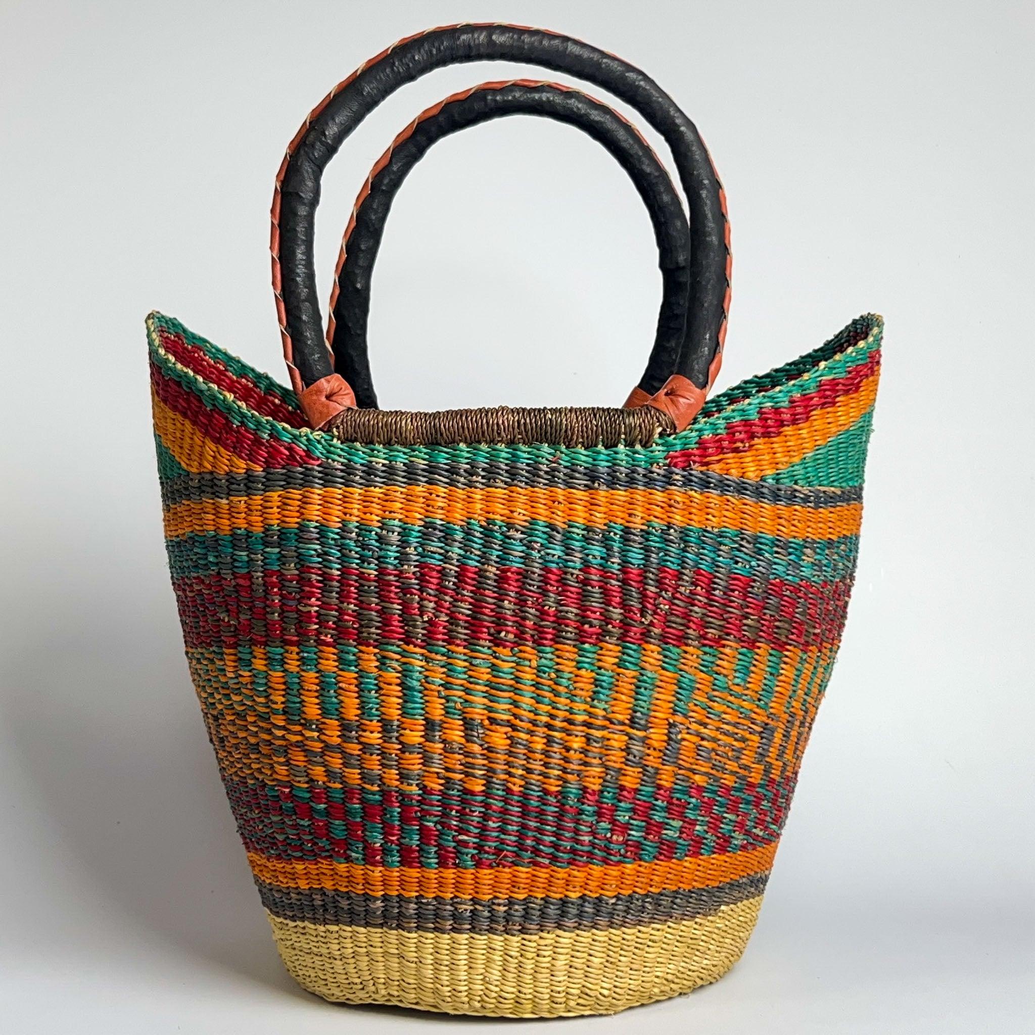 Close-up of a traditional African basket with a orange and teal stripe design and with black and tan handles.
