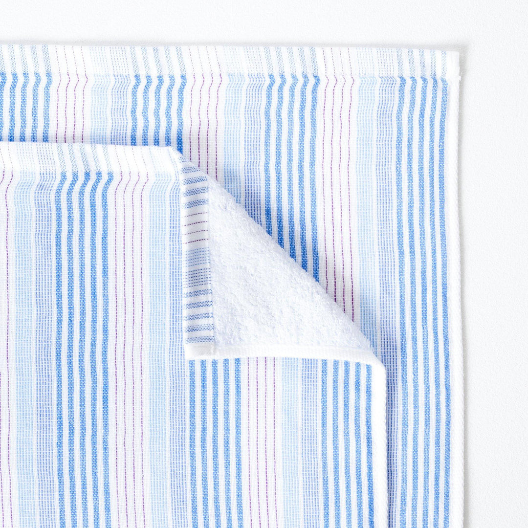 Close up image of blue, white and red striped baby or small towel.  The edge of the towel is folded down in one corner to show the soft terry pile on the reverse of the towel.