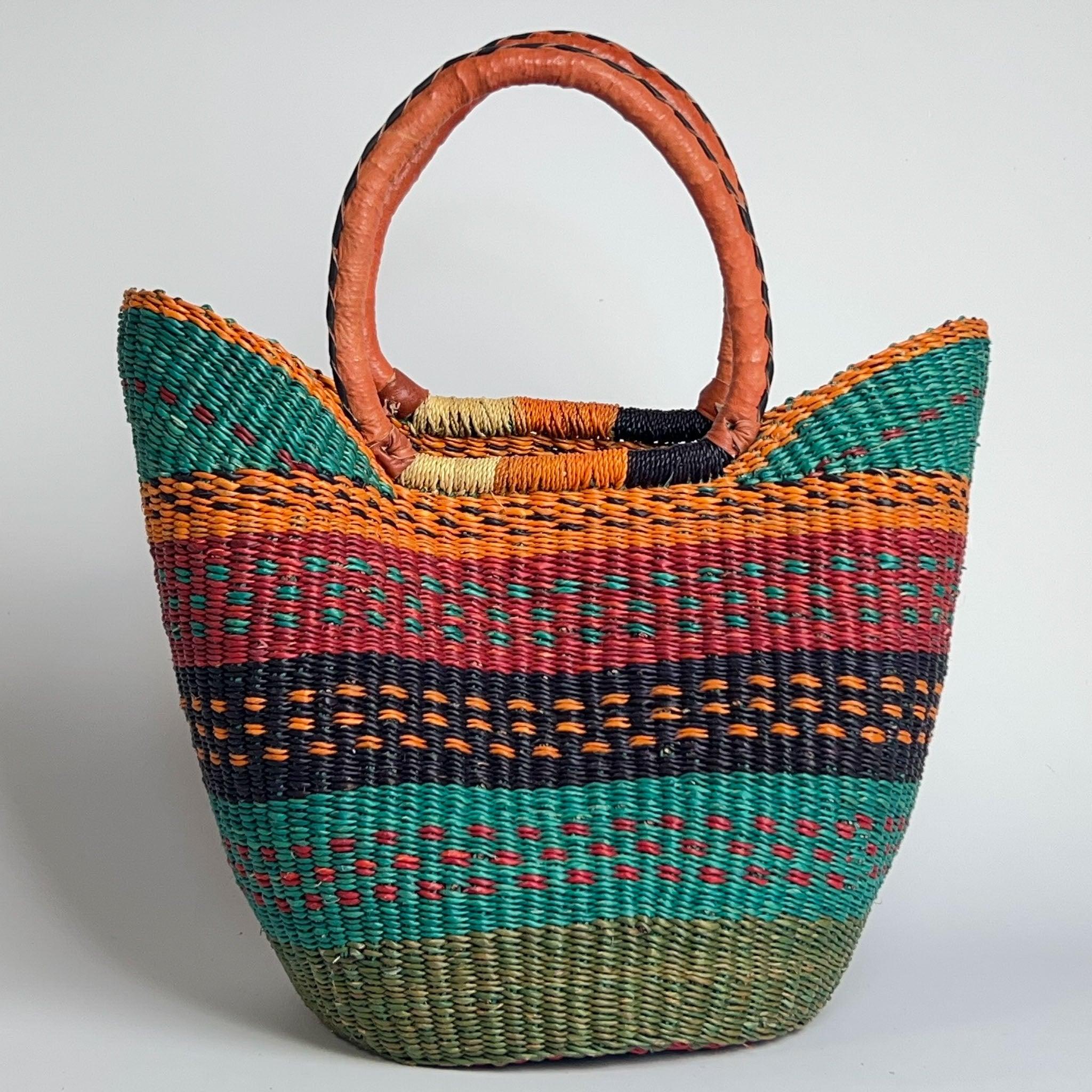 Close up of a traditional basket from Africa in the famous u shape style, with a unique design and tan leather handles.