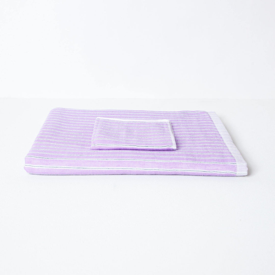 Baby bath towel folded flat with folded flannel.  The towel is lilac with a stripe design.