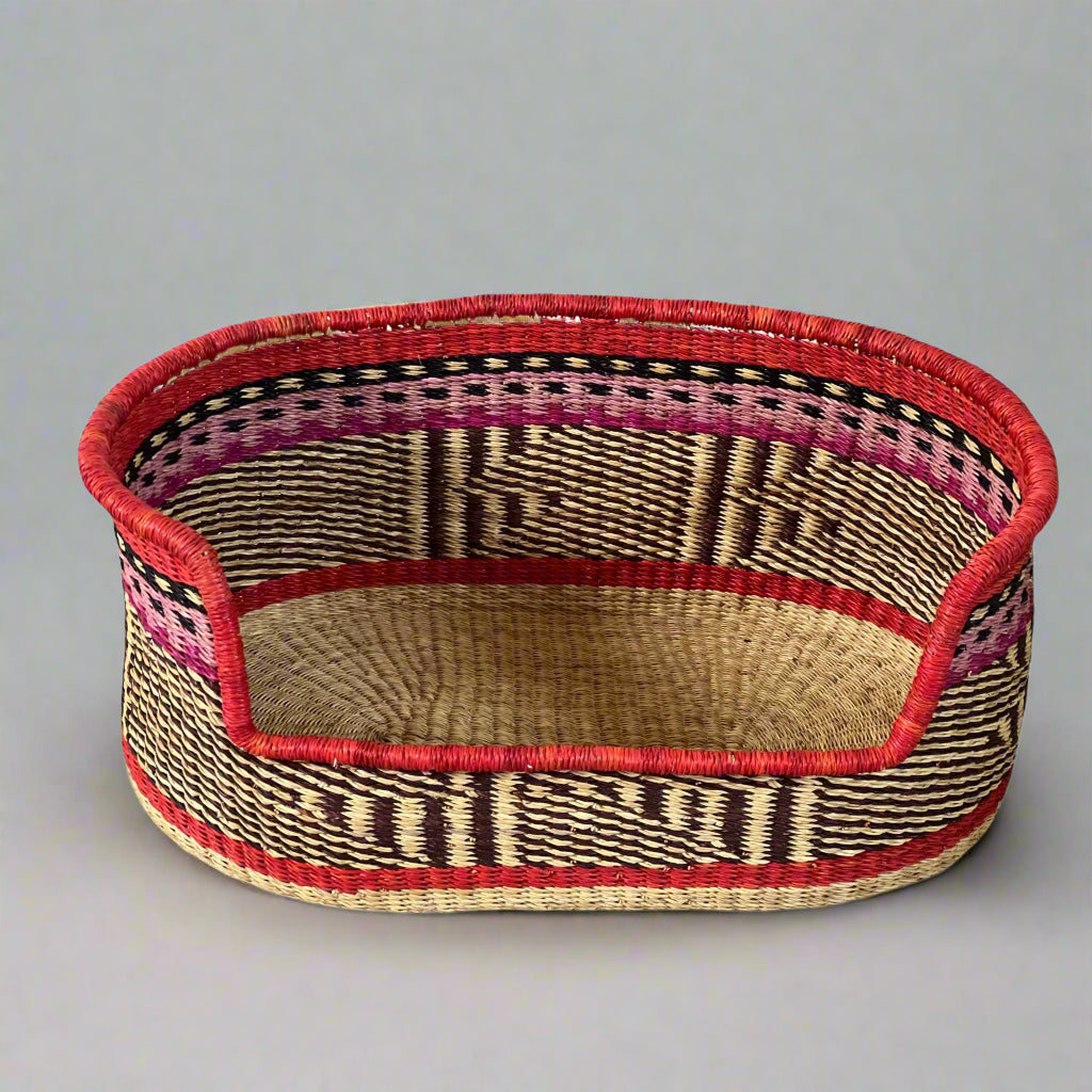 Oval dog basket in blue, pink and red design in studio setting