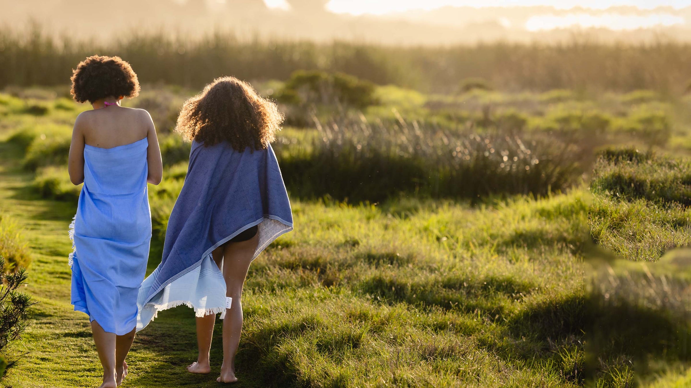 Mother and daughter walking home covered up by pretty blue beach towels