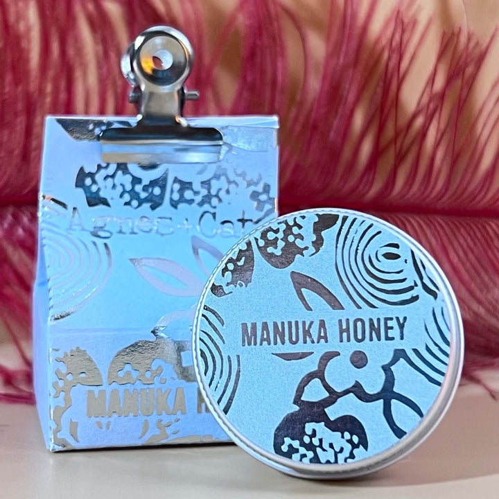 Manuka Honey lip balm tin shown outside of outer packaging