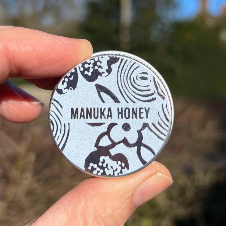 Hand holding Manuka Honey tin to give idea of size