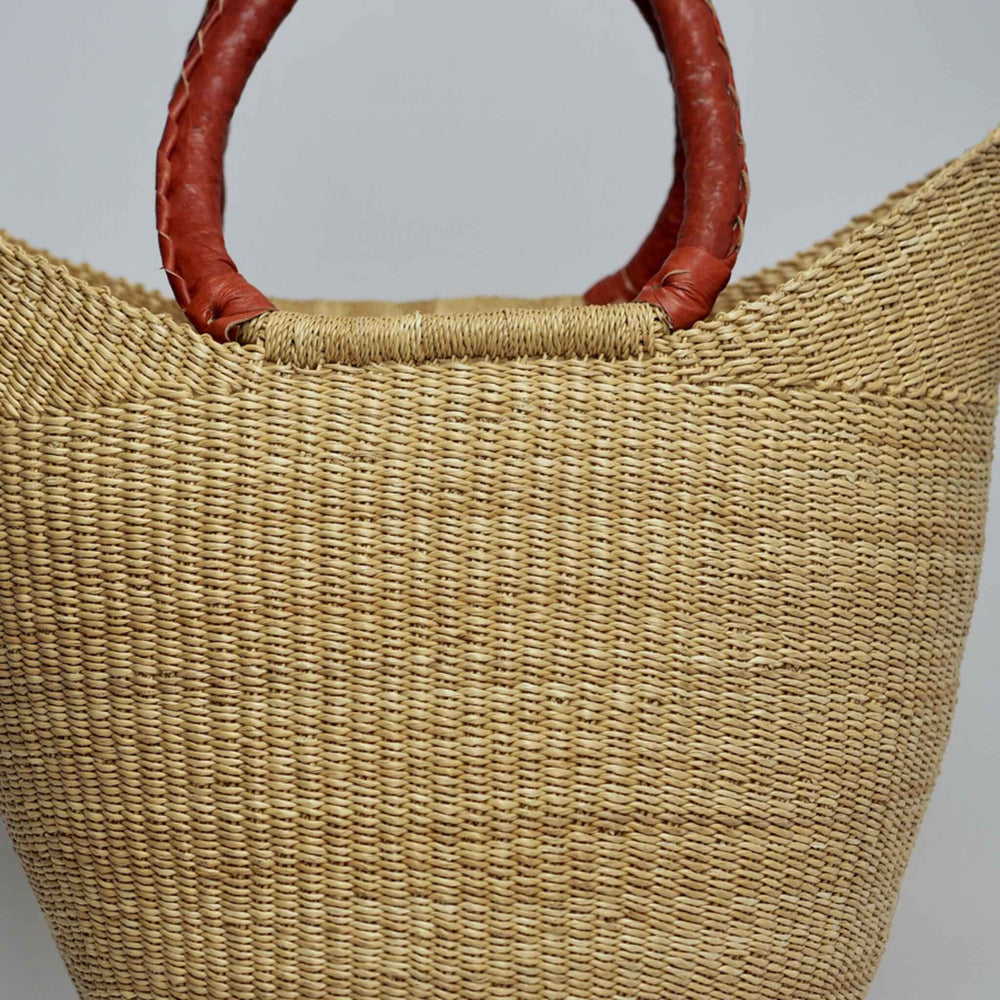 Close up of undyed basket with tan leather handles