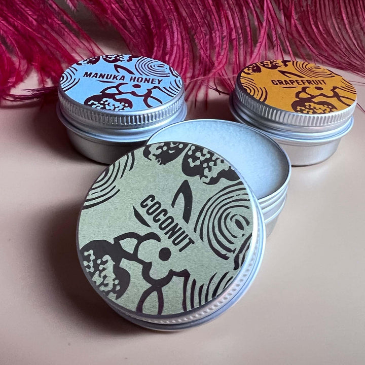 Trio of lip balm tins with a close up of Coconut, with lid off