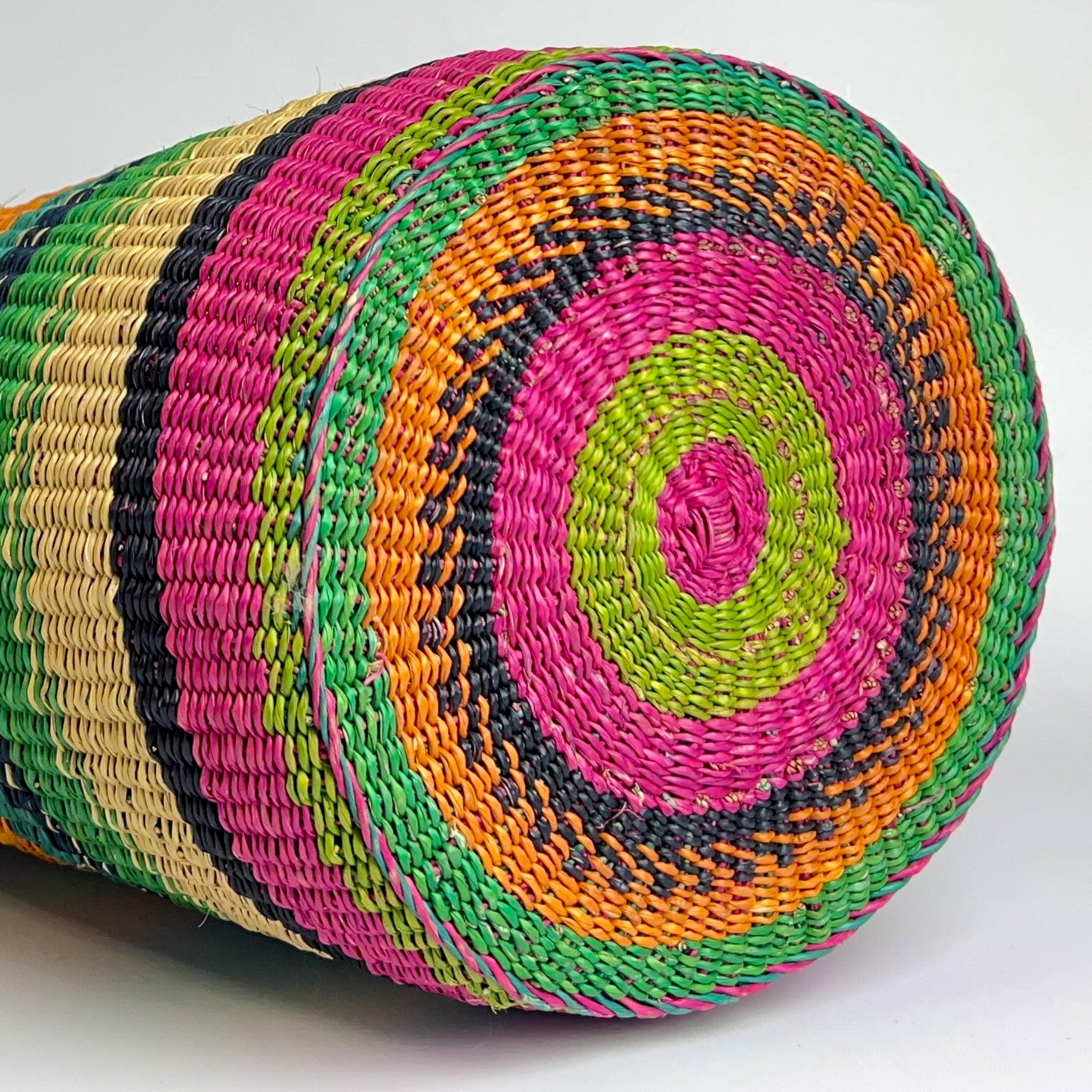 Basket on it's side showing off the colourful and striking design of the base, in pinks, orange and lime green.