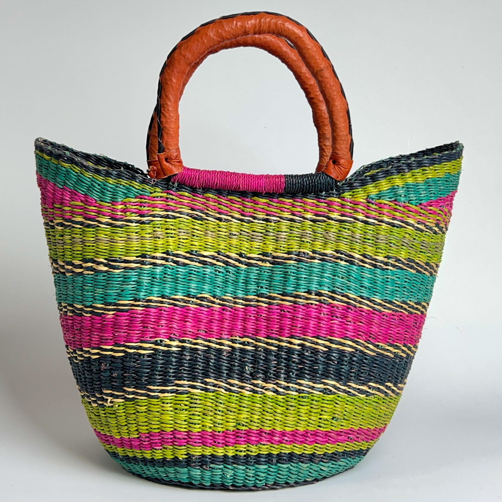 Traditional Ghanian shopper basket with colourful stripes in pink, blue and lime green and with black and tan handles. 