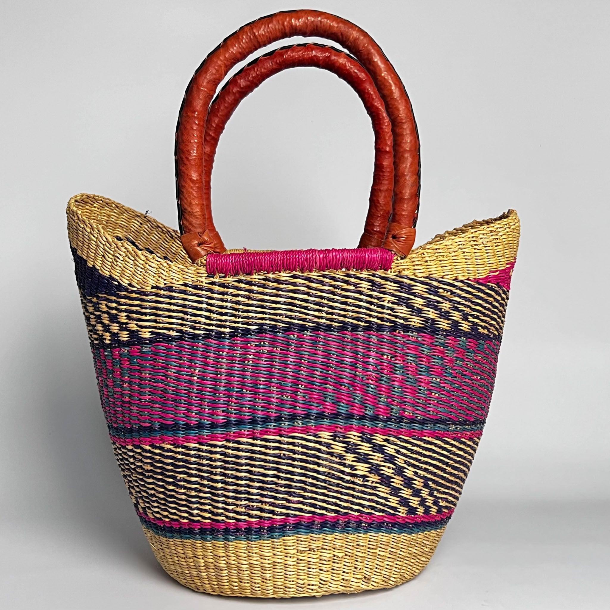 Close up of a traditional African U Shopper basket with tan leather handles and an attractive blue and pink design.