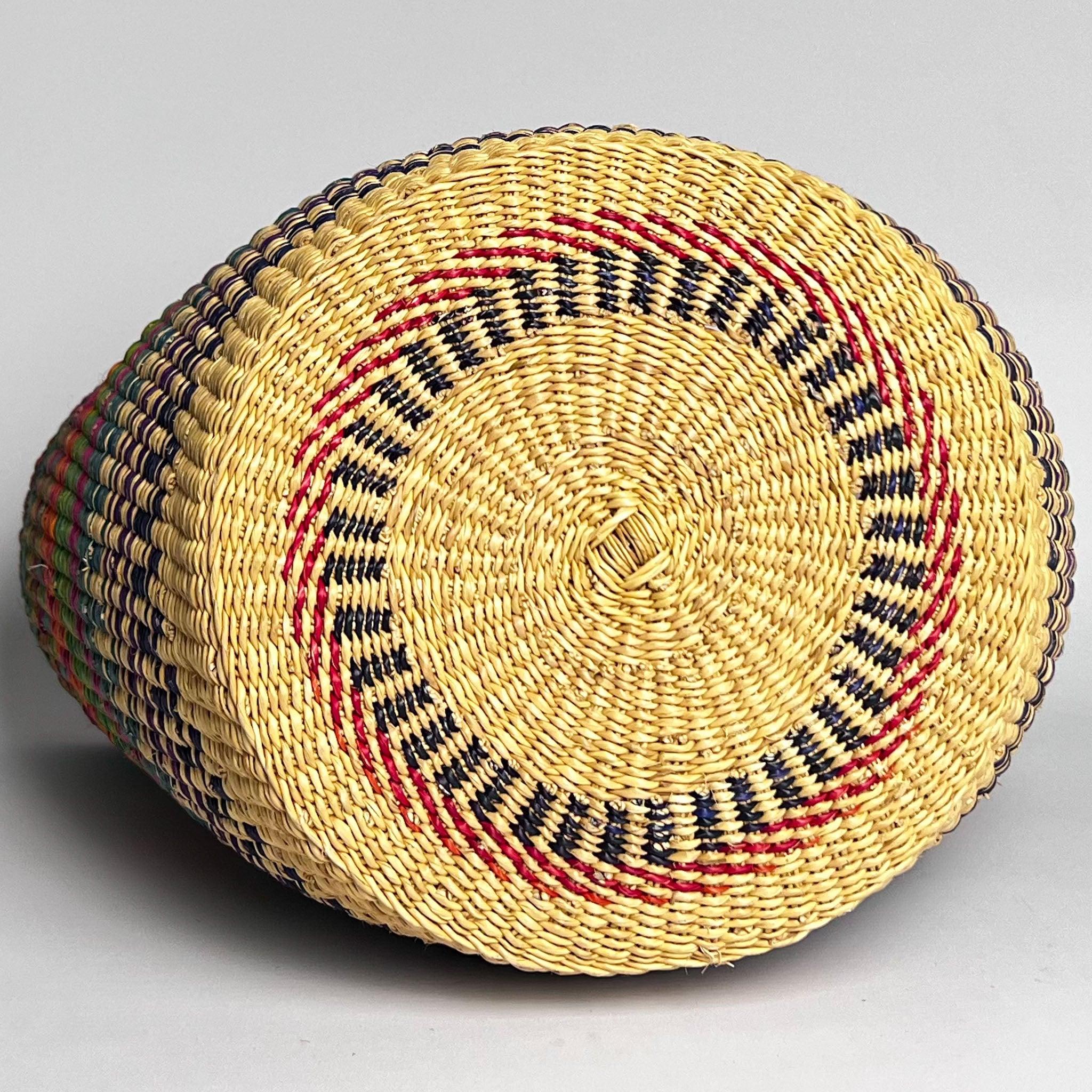 African traditional shopper basket, on it's side displaying the attractive design on it's base, woven in blue and red.