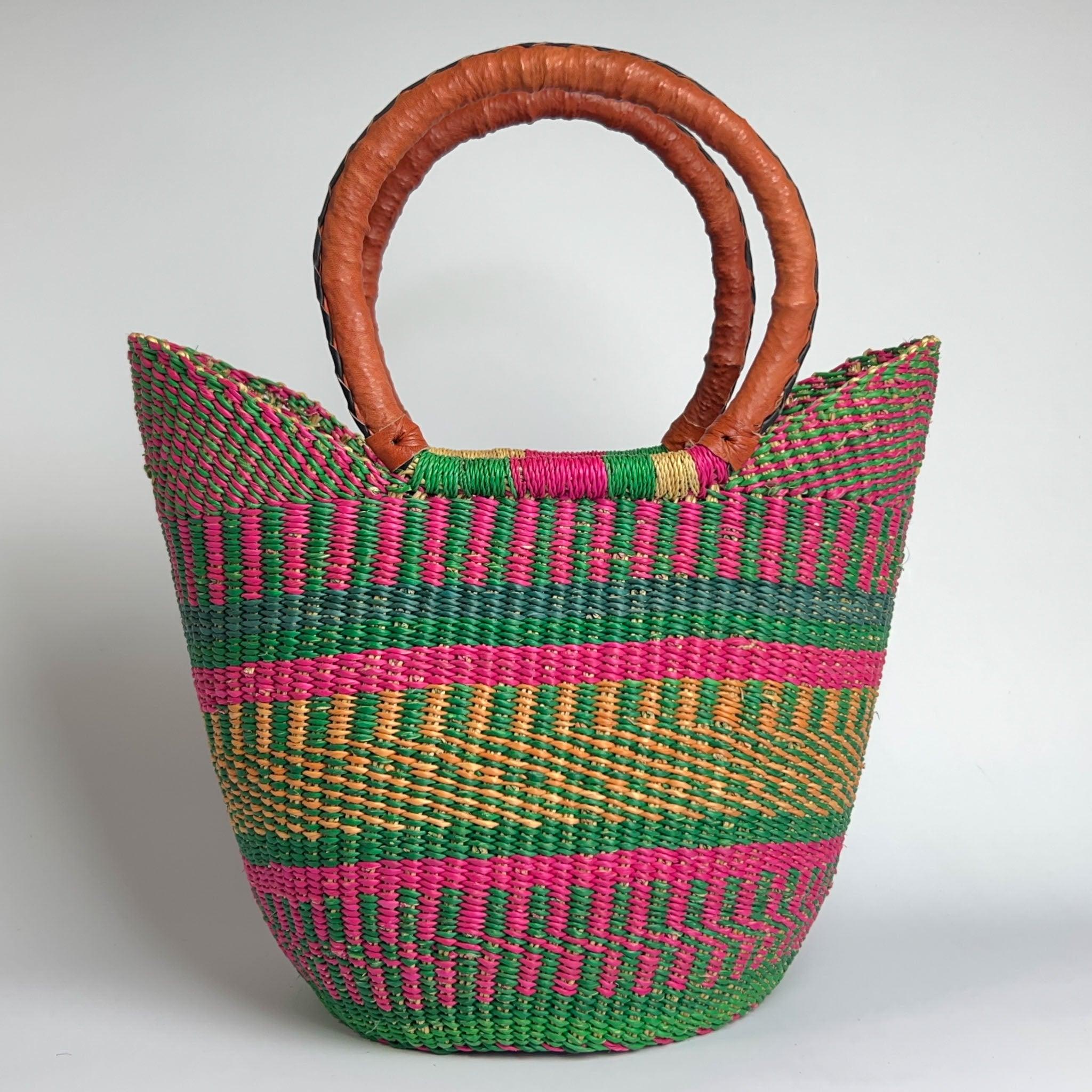 Summery African basket close-up showing off the vivid pink and fresh green colours and attractive leather handles.