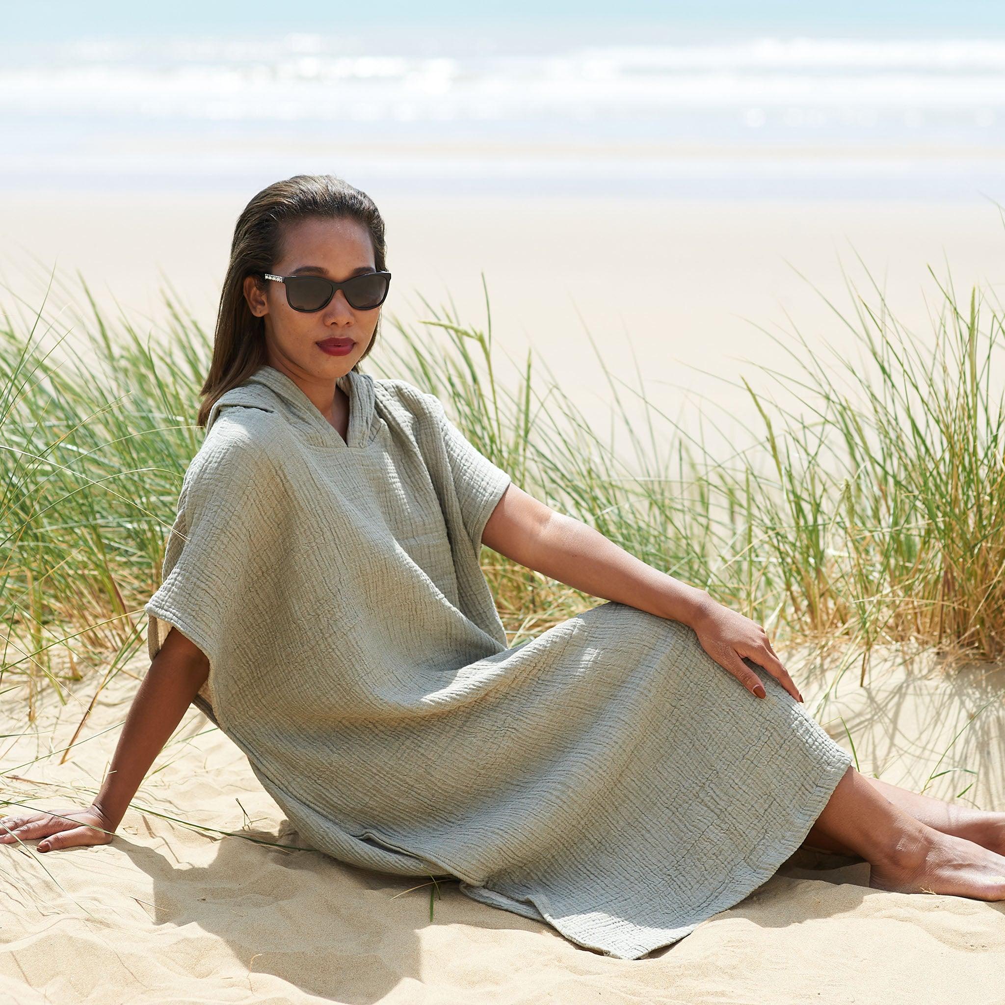 Lady sat at the beach wearing a Lorima beach changing robe and sunglasses.  
