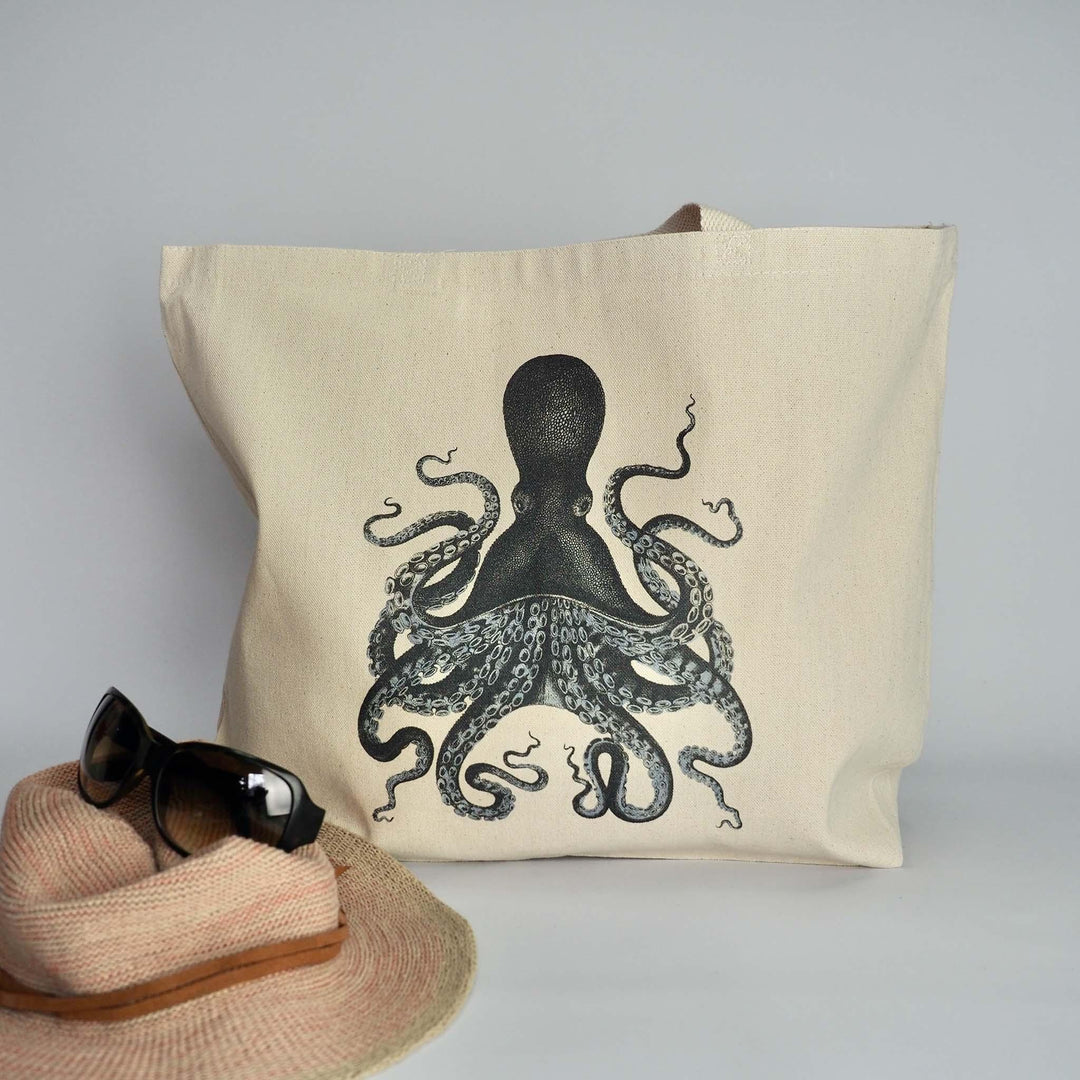 XL canvas tote bag with Kraken style octopus in inky blue with tentacles, accessorised with sun hat and sunglasses, ready for the beach.  