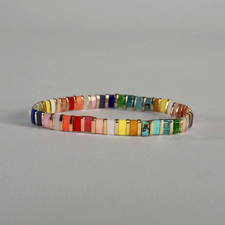 Single Miyuki Glass bead bracelet in rainbow colours, against a plain background